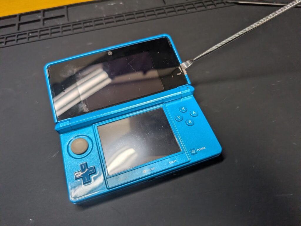 3DSの上側パネルに分解ツールを差し込んでいるときの写真
