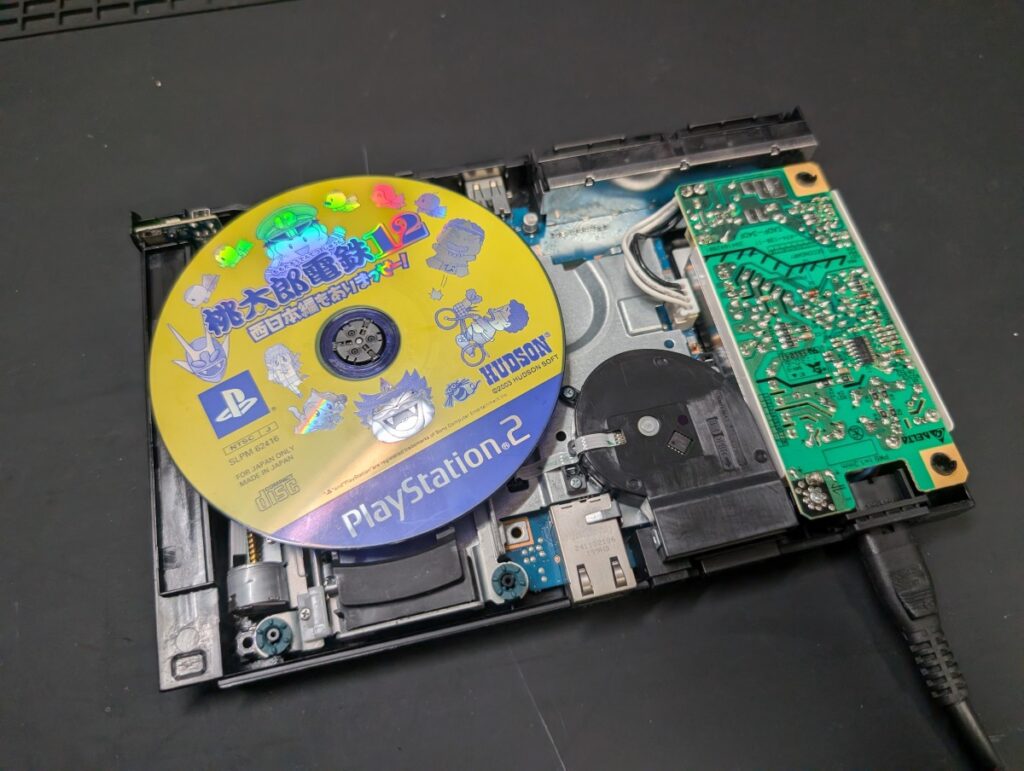 SCPH-90000の修理後の動作確認時の写真
CD規格ディスクを本体にセットしている様子