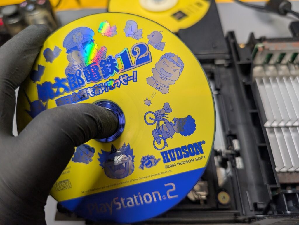 SCPH-50000のピックアップレンズ交換後の動作確認時の写真
CD規格ディスクを持っている様子